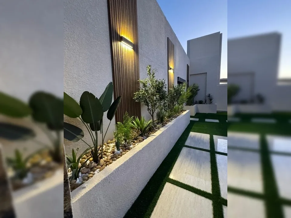 واجهة خارجية بألواح جدارية وحوض نباتات مضاء
